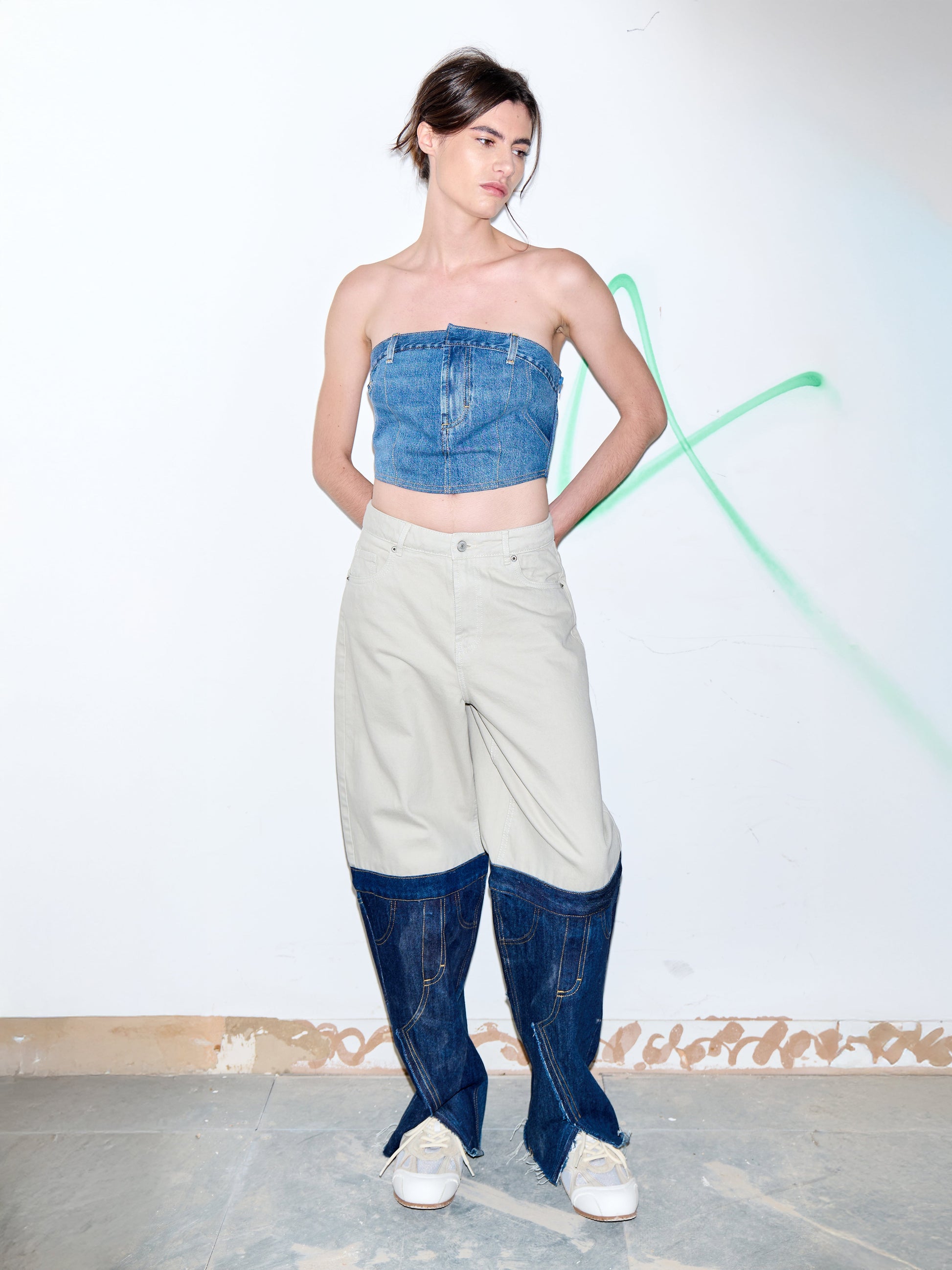 Woman wearing a denim strapless top and high-waisted jeans with a white background